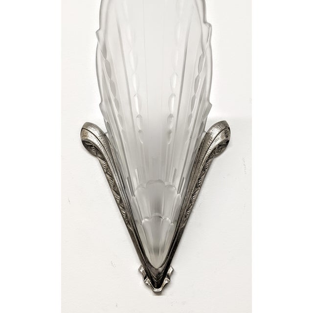 A pair of French Art Deco wall sconces created by E.J.G. Clear frosted molded glass shades in geometric design held by...