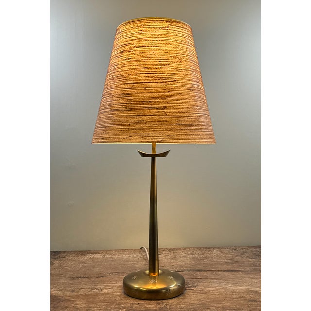 This mid century modern Stiffel table lamp features a brass finished metal base with engraved starburst detailing, with a...