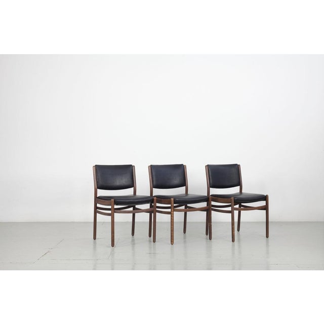This set of three wooden chairs was made in Italy in the 1960s. The seat and the backrest are covered in black imitation...