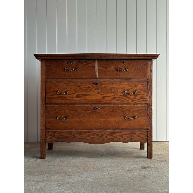 Solid oak chest of drawers with two over two drawer configuration and original brass bail hardware. Paneled sides and...