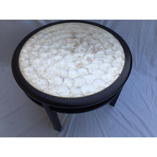 Mahogany round coffee/ side table with Capiz shell top with brass border. Collection of rCannell & Chaffin. It has ebony...