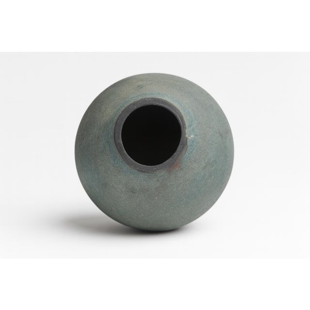 A studio raku vase defined by its textured exterior and abstract patterning. The vessel’s flared mouth and incised base...
