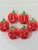 A playful set of large strawberry-shaped mercury glass Christmas ornaments featuring vibrant red bodies with bright green...