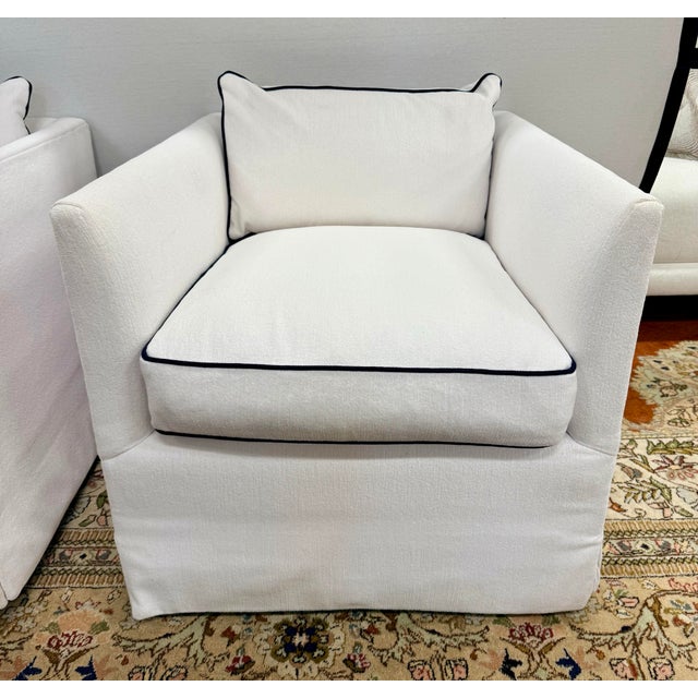 Chic pair of Serena & Lily white slipcovered swivel chairs with clean-lined arms and tailored skirts, finished with crisp...