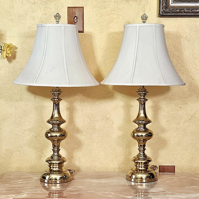 Elevate your space with this stately pair of tall brass table lamps, a perfect blend of Hollywood Regency elegance and...
