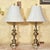 Elevate your space with this stately pair of tall brass table lamps, a perfect blend of Hollywood Regency elegance and...