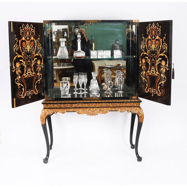 A fabulous vintage polychromed black lacquered and marquetry inlaid cocktail cabinet-on-stand, circa 1930 in date. The...
