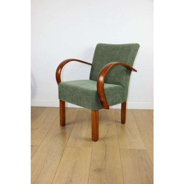 Bent vintage Art Deco loft armchair in olive green. A stylish, curved chair with a vintage Art Deco design, perfect for...