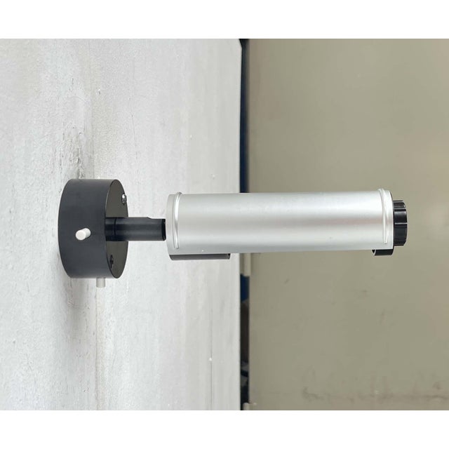 Minimalist wall light from the German manufacturer Erco. The light features a simple cylindrical shape. Its distinctive...