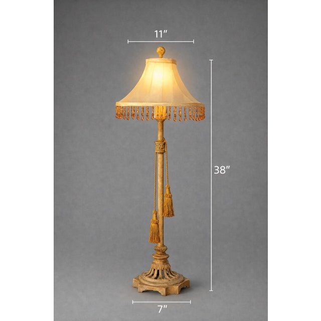 A dramatic 38-inch Hollywood Regency style table lamp featuring a solid cast iron base, carved column detail, dual tassel...