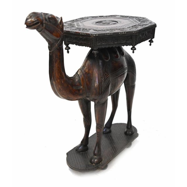 A superb anglo-indian carved hardwood camel side table, dating to circa 1820, finely modelled in the form of a standing...