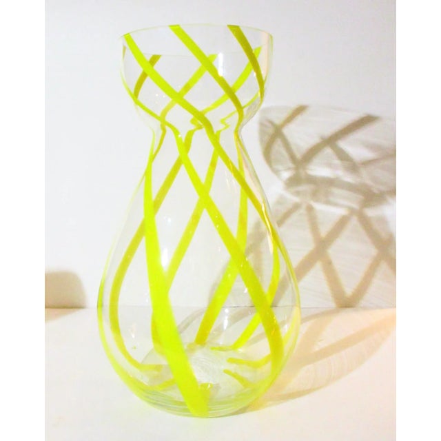Tall clear-blown glass vase with several opaque yellow candy stripes swirling around the body. Bulb bowl mounts with a...