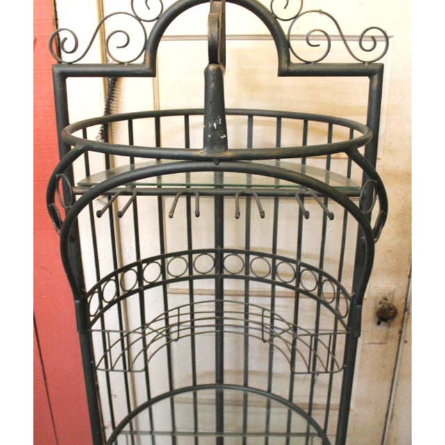 Six foot tall storage unit for wine and glasses. Unique round shape with ornate iron scrolling and two glass shelves....