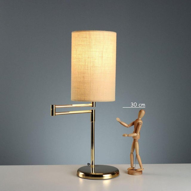 1980s-style table lamp with a swivel arm for directional and customizable lighting. The brass-plated metal frame lends a...