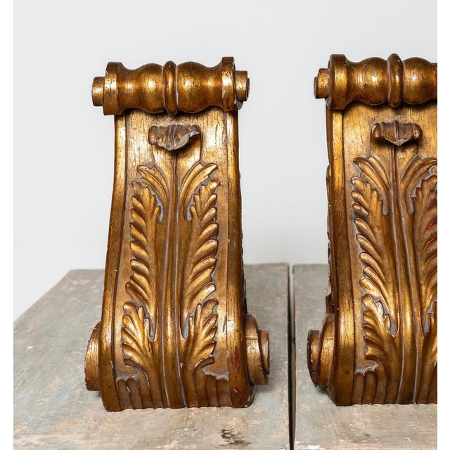 A striking pair of antique carved giltwood architectural corbels, each measuring approximately 18 inches high by 10 inches...