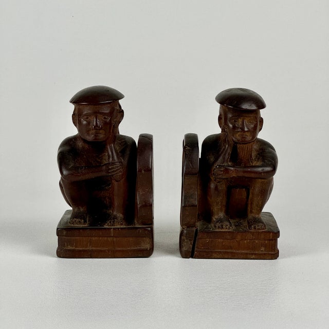 A vintage pair or hand carved wooden bookends of Asian men sitting with face in palm and doing much thinking. The wood is...