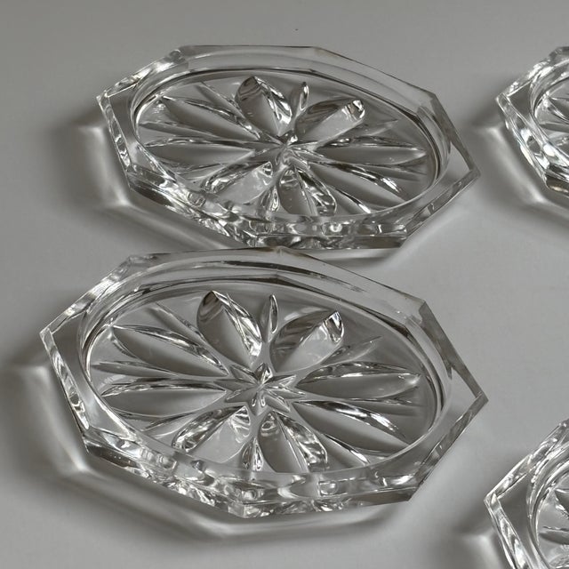 A striking set of five vintage clear glass coasters featuring a crisp octagonal silhouette and an elegant molded twelve-...