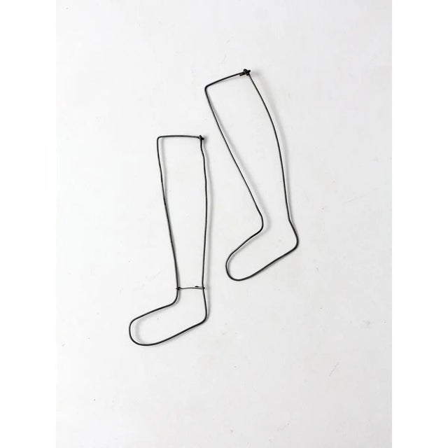 A pair of antique industrial children’s sock stretchers, crafted from slender metal wire and designed to hold stockings in...