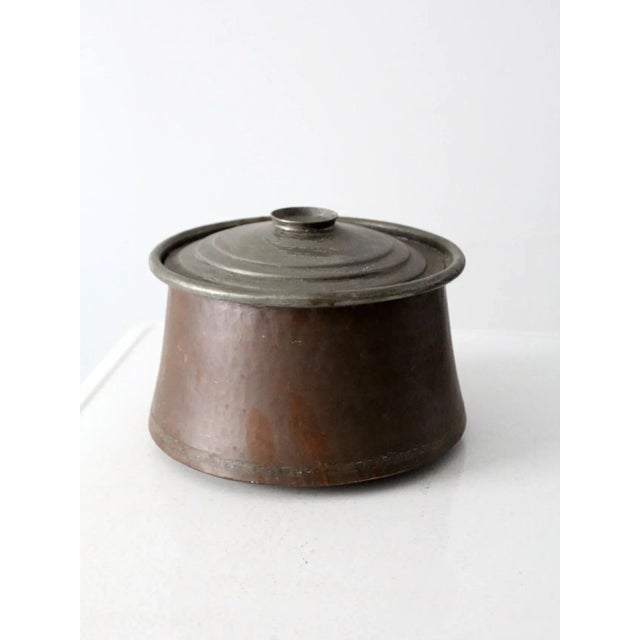 This is an antique hammered copper cauldron pot. The rounded bottom basin features tapered sides and a rimmed top lip....