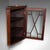 This is a small antique glazed corner cupboard. An English, mahogany wall display cabinet, dating to the Edwardian period,...