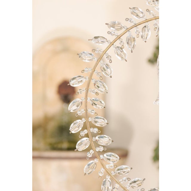 A pair of French crystal light fixtures from the early 20th century, with campanula, ribbon and rosette motifs. This pair...
