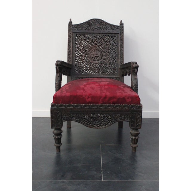 Anglo Indian colonial armchair, carved out of teak wood, under the armrests stand 2 lion heads, on the central rosette...