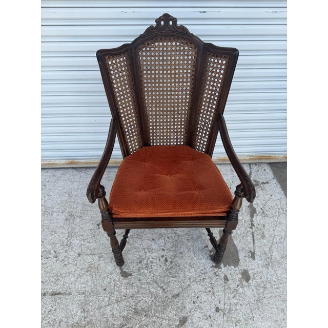 This stunning antique armchair features an intricately carved wooden frame with a unique cane backrest design that brings...
