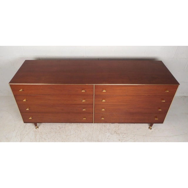 This stunning vintage modern dresser features eight large drawers with sculpted brass pulls on each. A unique design with...