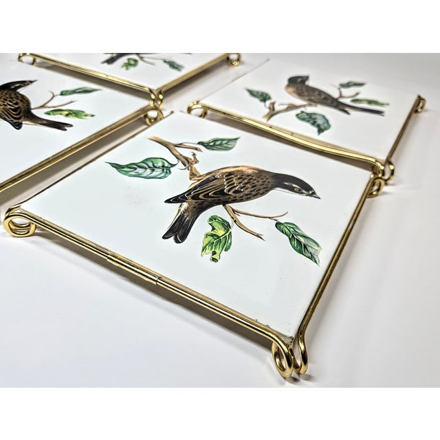 Four vintage tiles- each with a perched bird and set onto a gold-colored trivet frame. Several have tiny "flea bite" chips...