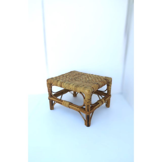 A rectangular wicker footstool with weaved top and wrapped rattan legs, circa mid-20th century. A great piece to rest...