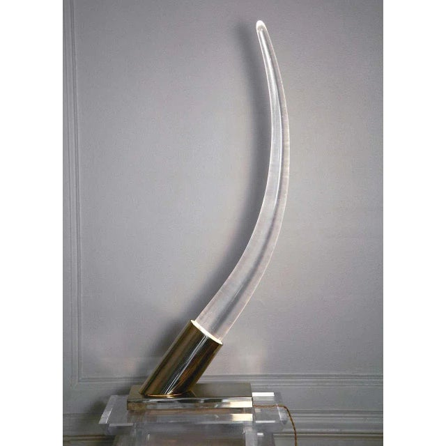 This acrylic glass tusk table lamp on chromed metal base was produced in the 1970s. Up to 250V (Europe/UK Standard).The...