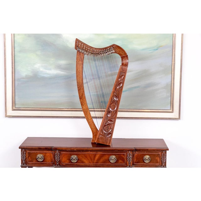 A small carved wooden Celtic 19-string table-top harp with a curved neck decorated in intricate knot work patterns and a...
