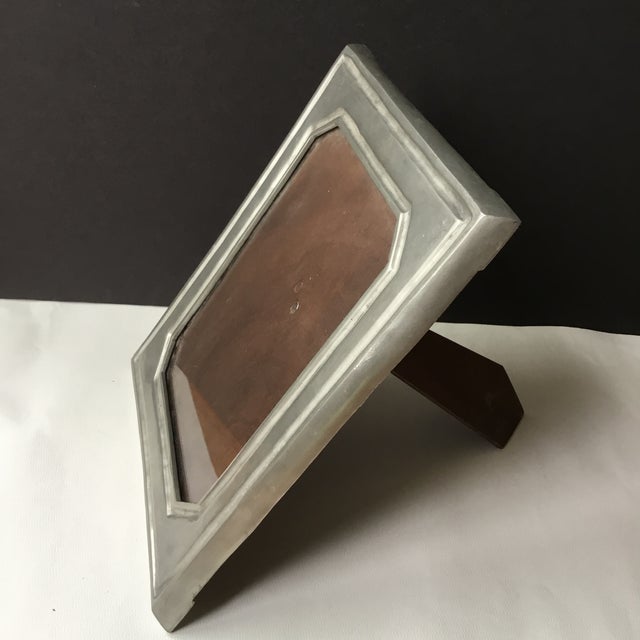 Features a pewter frame, glass insert/cover, a wooden backing and octagonal inner framing. Stamped on one side of the...