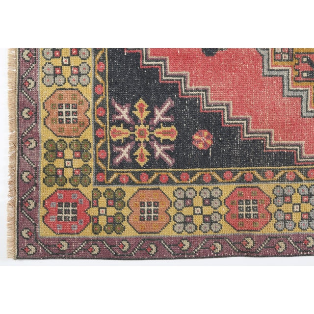This vintage handwoven Turkish rug features a striking stepped-medallion design set against a softly faded red field. Rich...