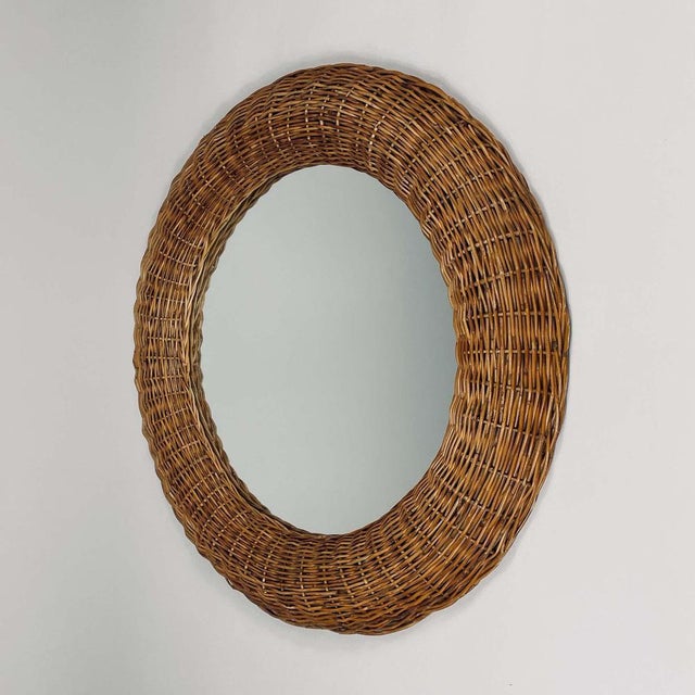 This vintage wall mirror was designed and manufactured in France in the 1950s. It features a hand woven rattan round frame...