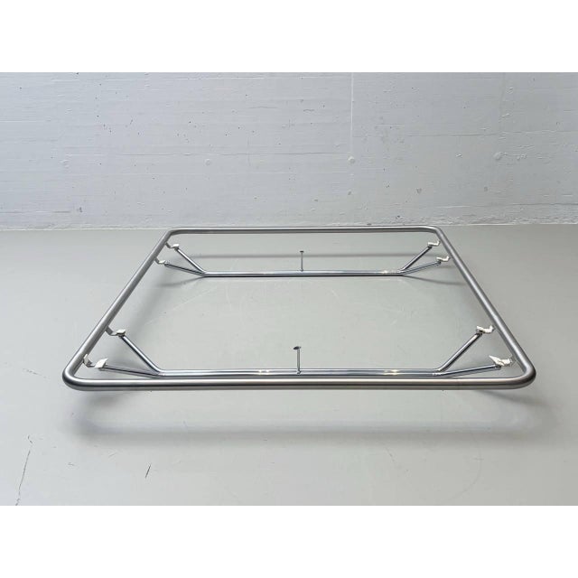 A minimalist bed frame designed by bruno huwyler, featuring a surrounding frame of chrome-plated steel tubing. The clear,...