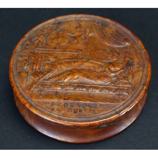 The circular lidded box depicting a woman reclining on a Recamier playing the harp. The underside with a star surrounded...
