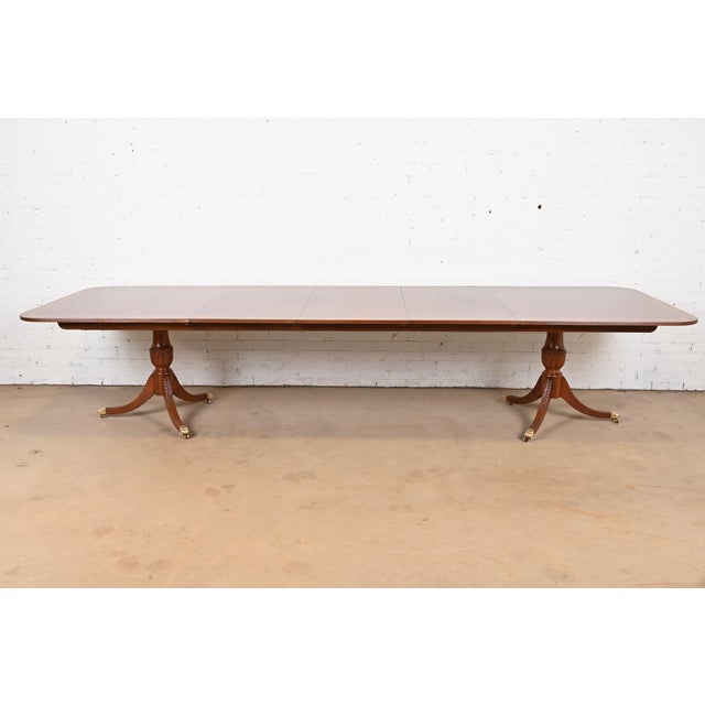 An exceptional Georgian or Regency style double pedestal extension dining table In the manner of Baker Furniture USA,...