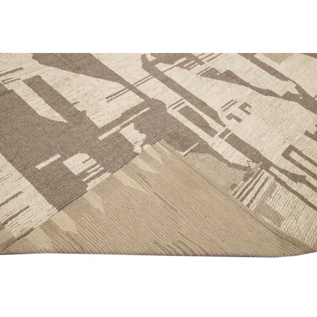 Beautiful Moroccan style handmade wool rug with a beige field. This Modern rug has brown, yellow, and blue accents...