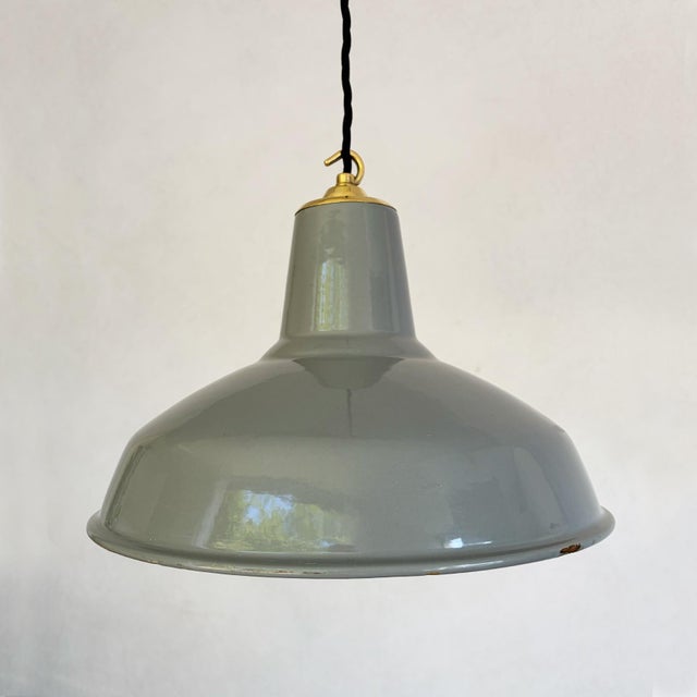 A pressed steel shade finished in grey vitreous enamel over a white enamelled interior, with a rolled rim and a tall...