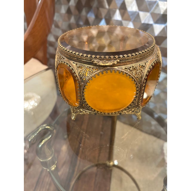 Lovely French brass ormolu and amber glass round jewelry casket box having ornate feet and circular glass panels around...