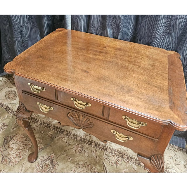 A lowboy chest by Baker Furniture. Brass hardware with a sculpted bevel edge to the top, cabriole legs, and pad feet....