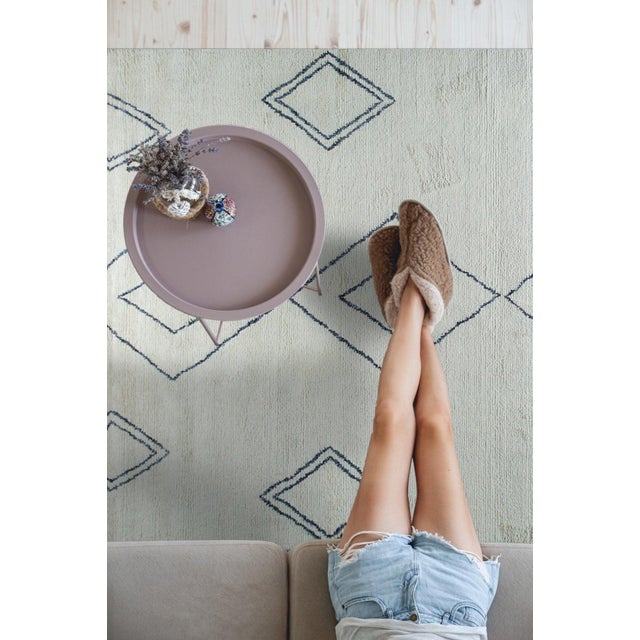 A hand-knotted wool rug, made in India and measuring 4' x 10'. Geometric drawing - repeating motifs held inside strong...
