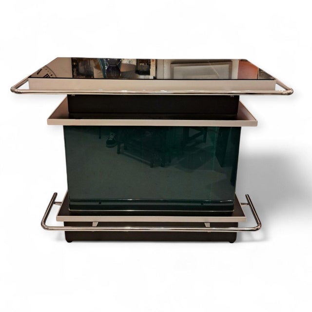 Eighties-style chrome bar with smoked glass in shades of green and black. Bar set with two chrome stools upholstered in...