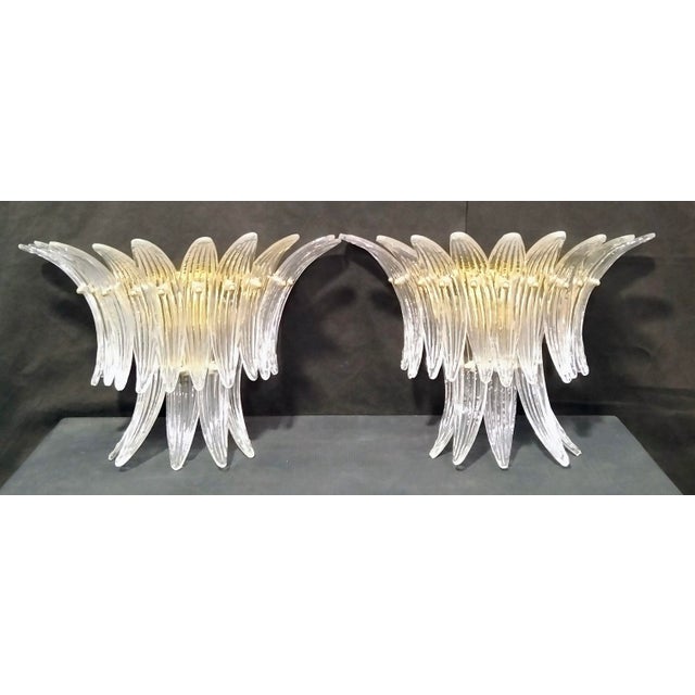Pair of hand-crafted Murano glass palmette wall lamps. Transparent in color with brass-colored metal frame. Two E14 lamp...