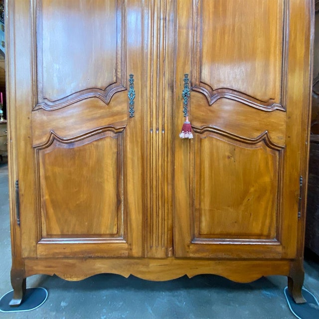 DETAILS An antique French cherry wood wardrobe with inlaid vining panel beneath the curved molded cornice. A fluted post...