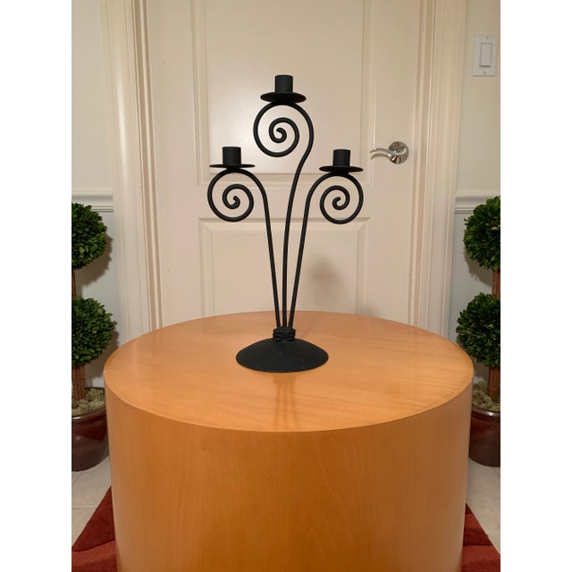 This whimsical candelabra in wrought iron adds fun to any table or shelf. It is 16" tall and 9" wide; the base is 6" in...