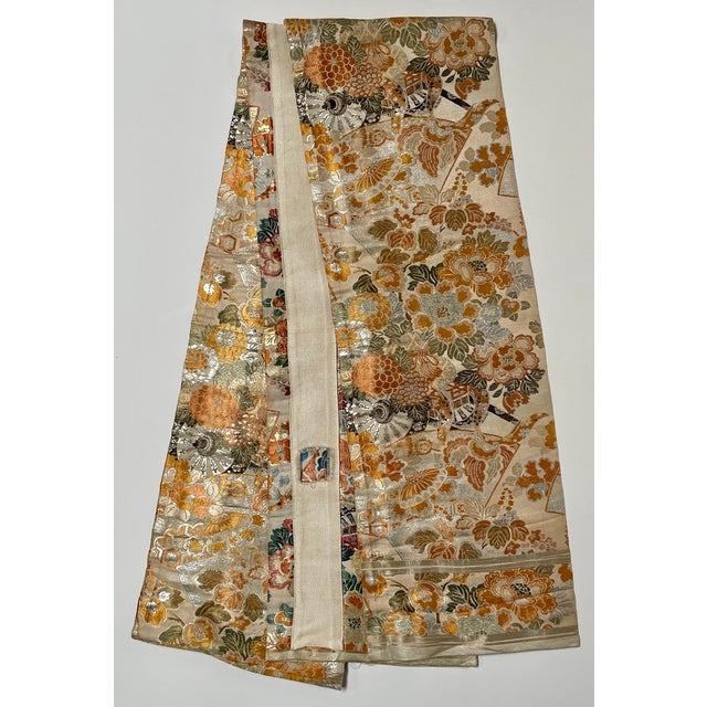 This is an exquisite silk floral brocade with silver metallic, orange, and olive, on a champagne neutral ground depicting...