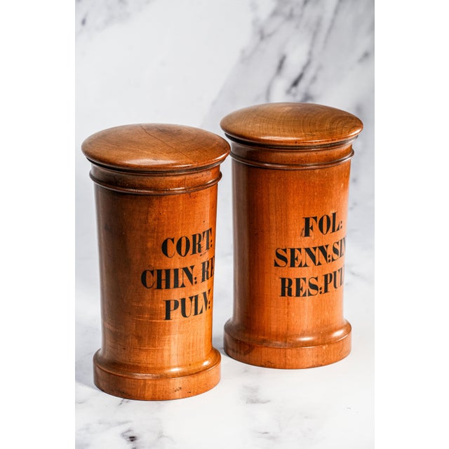 A captivating and richly authentic pair of antique wooden apothecary jars, beautifully embodying the craftsmanship and...