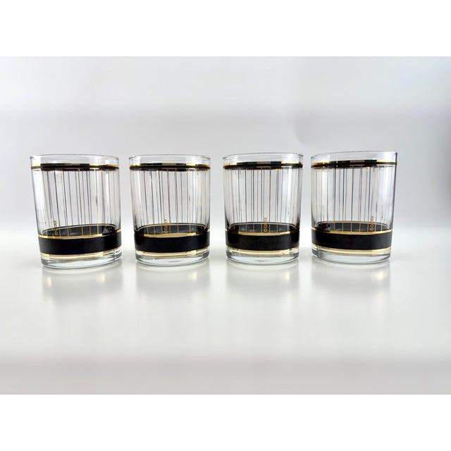 Sophisticated mid-century barware set featuring four Culver lowball glasses paired with a coordinating black and gold ice...